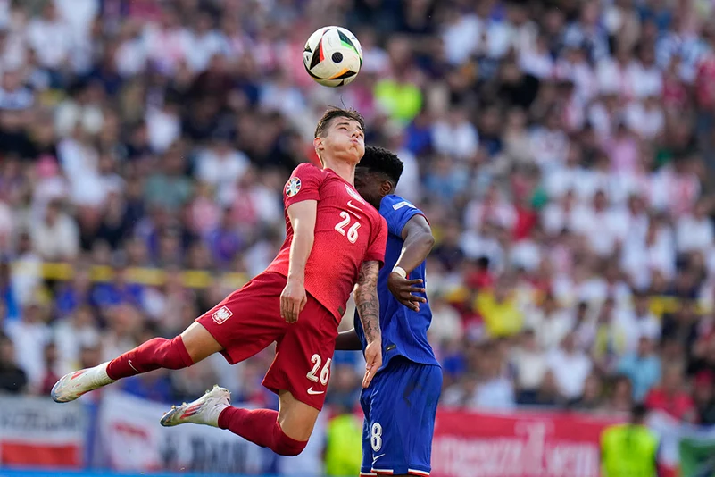 Kacper Urbanski goes up for a header next to Aurelien Tchouameni